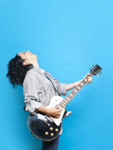 mulher-toca-guitarra-fundo-azul-porto-640x853